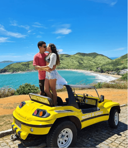 Pareja disfrutando un paseo en buggy amarillo con vista a la costa de Búzios